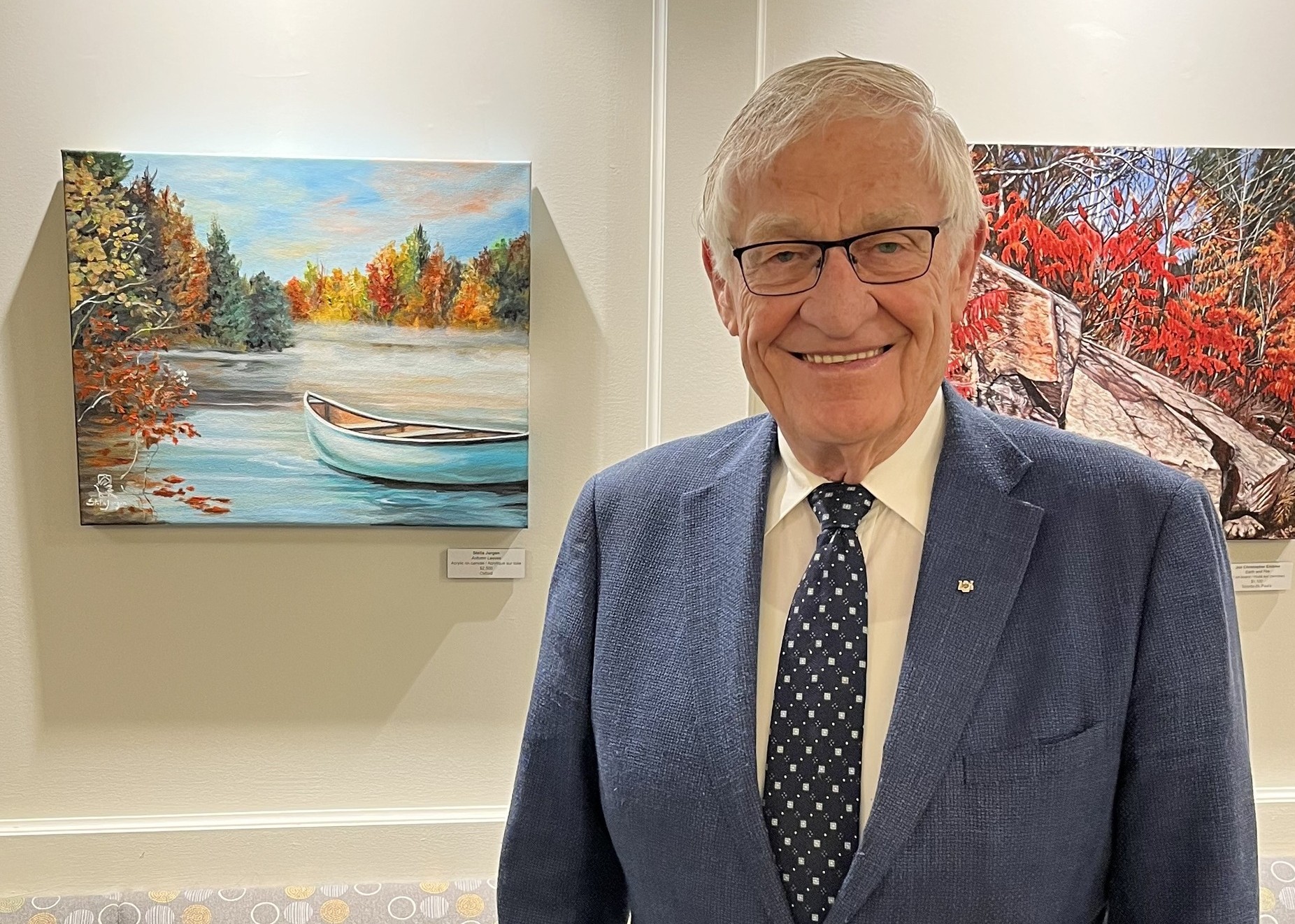 April 20, 2026: Ernie Hardeman, MPP Oxford poses in front of Autumn Leaves by Stella Jurgen at the Art à la Carte - Celebrating Ontario Artists - Ontario Legislature, Dining Room.